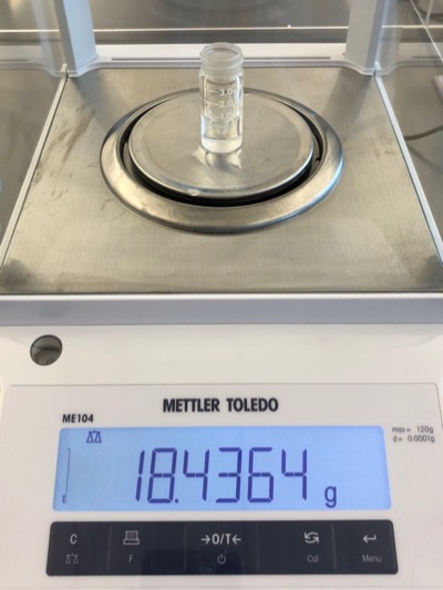 a photograph of the empty 3-mL conical vial on an analytical balance. The mass of the empty vials reads as 18.4364 g.