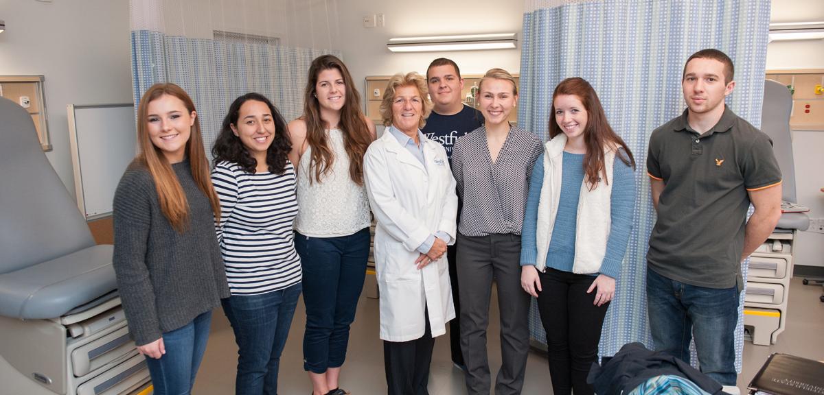 Multiple students in the Health Sciences program stand with their professor in a clinical setting.