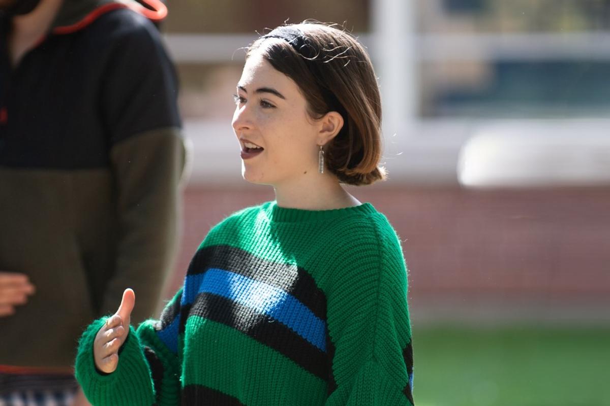 Music student in green striped sweater singing.