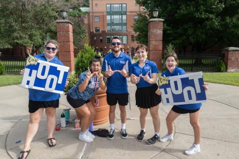 A small group of new students wearing blue shirts and holding blue and white signs that say, "Hoot Hoot". The new students are celebrating move-in weekend, which began on September 1.