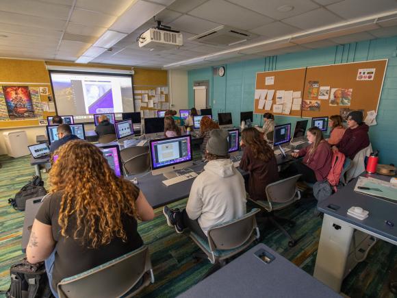 Students in a graphic design class with instructor giving a presentation.