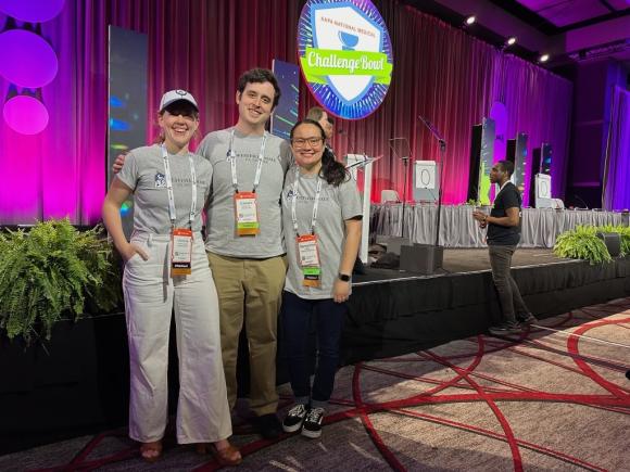 Students at the American Academy of Physician Assistants (AAPA) National Conference in Houston, Texas. Three pose in front of a neon sign that reads "The Challenge Bowl", a trivia game for PA students across the country.