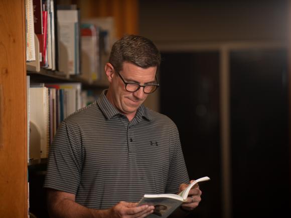 Graduate student reading a book in the library.