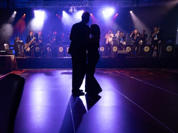 Two dancers in shadow during the Blue Diamond Ball at MGM Springfield's Aria Ballroom. A band plays behind them.