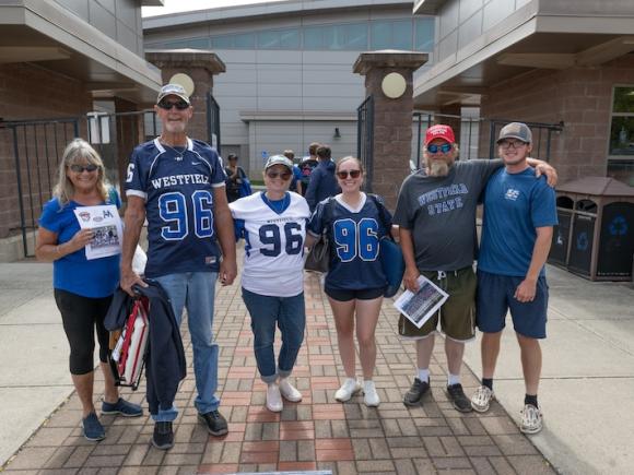 A family all in dark blue Owl merchandise as part of the 2024 Family Weekend event. Several family members cheer on their new student by wearing official Owl merch.