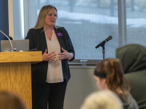 Woman stands at podium speaking to an audience