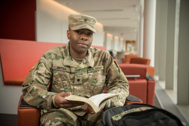 veteran student in uniform with book, looking at camera