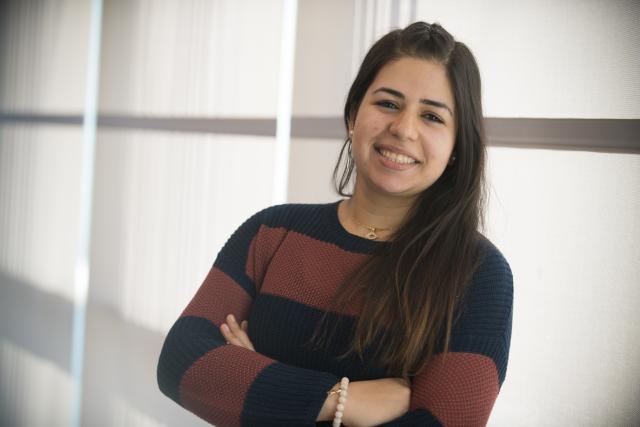 Smiling female student standing in front of the large windows in the Stevens Center