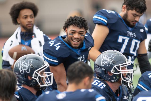 Westfield State footballs player smiles at his teammates on the sidelines during a game