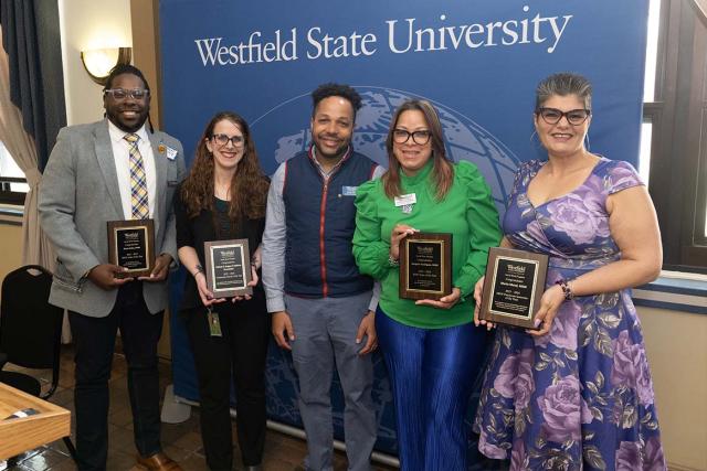 Multiple faculty members stand together while holding award plaques at the Westfield State University Social Work Clinical Conference.