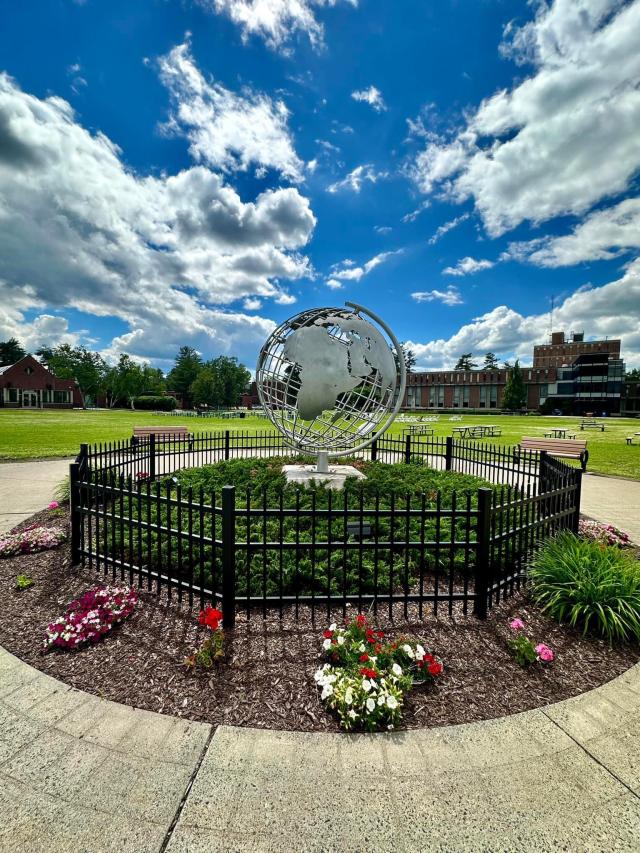 Campus globe in the summer with blue skies and flowers