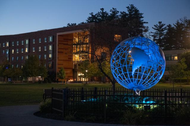 Campus globe at night with University Hall in the background.