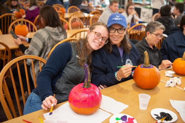 Two family members painting pumpkins at Family Weekend.