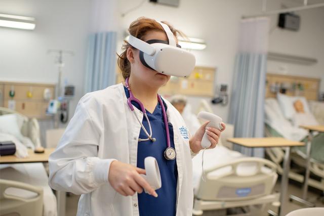 A nursing student wears a virtual reality headset in the nursing simulation lab.