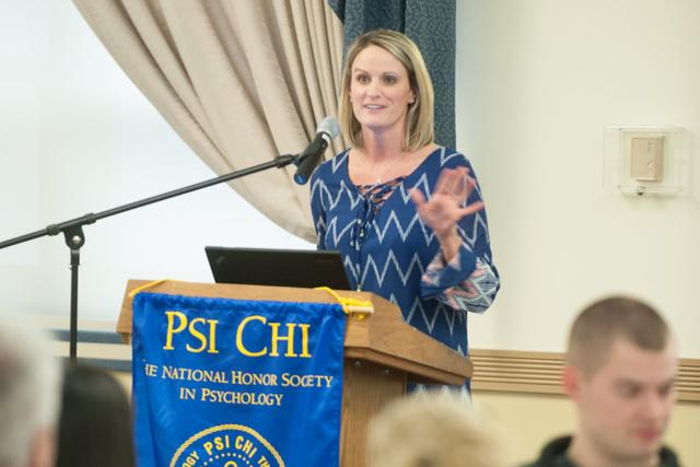 A Westfield State University psychology professor speaks from a podium at an event for The National Honor Society in Psychology.