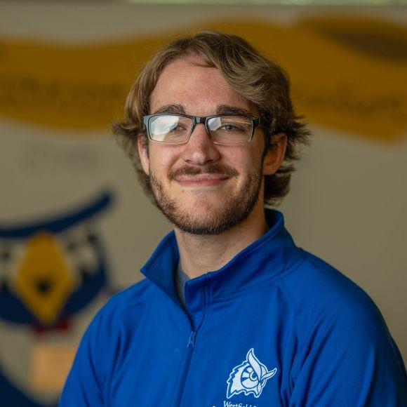 SGA President Justin smiling wearing a blue SGA shirt.