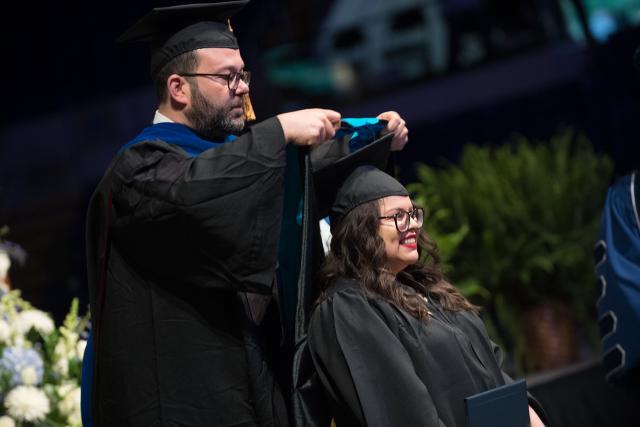 MPA Program Director placing a graduation hood on a student during the commencement ceremony.