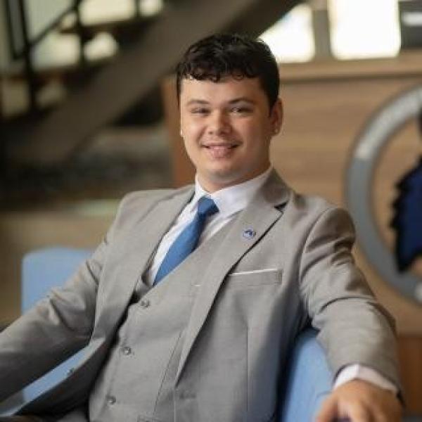 Aidan Gomez wearing a suit smiling.