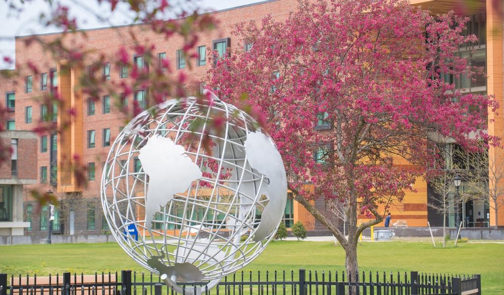 Campus globe in the spring with pink flowering trees.