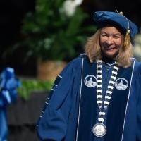 President Linda Thompson at the Undergraduate Commencement Ceremony. She is dressed in blue robes and a blue cap.