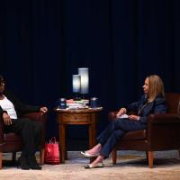 two women sit on a stage in conversation